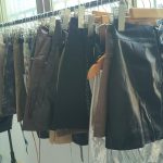 Denim skirts, PU-style skirts and shorts hanging on a rack
