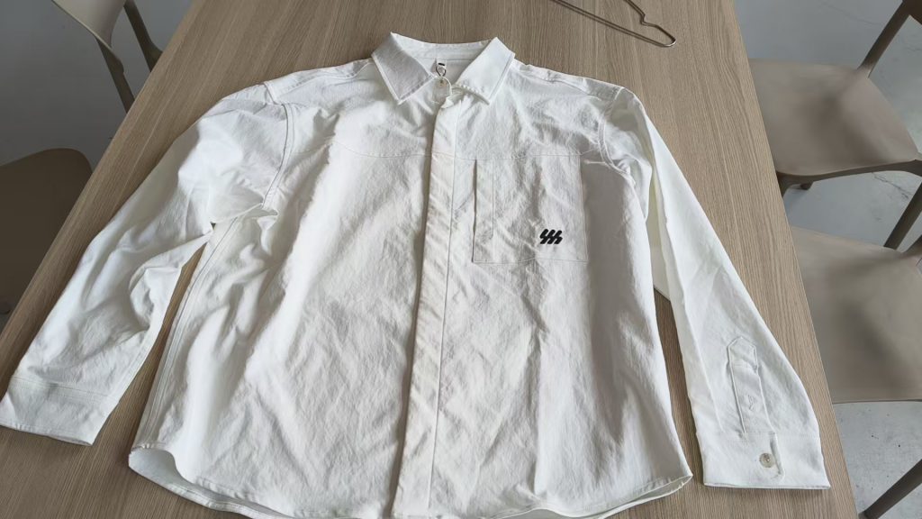 White poplin shirt laid flat on a table, front view